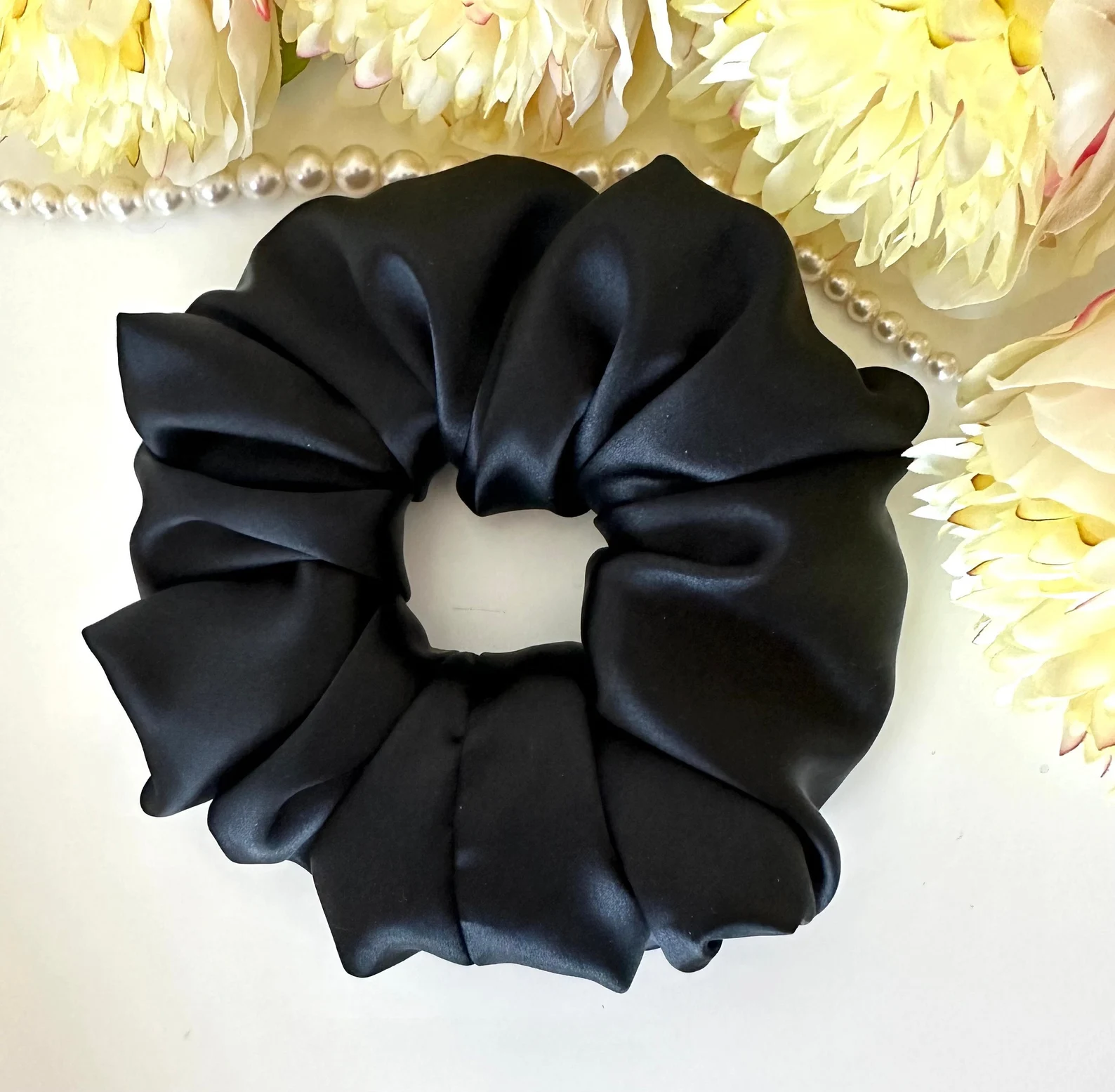 Nagy fekete szatén scrunchie hajgumi virágok és gyöngysor előtt